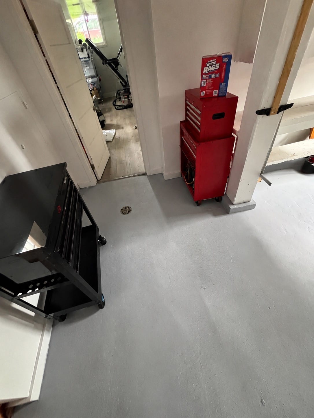Coated gray basement floor after work, with the original floor drain left exposed and clear of coating