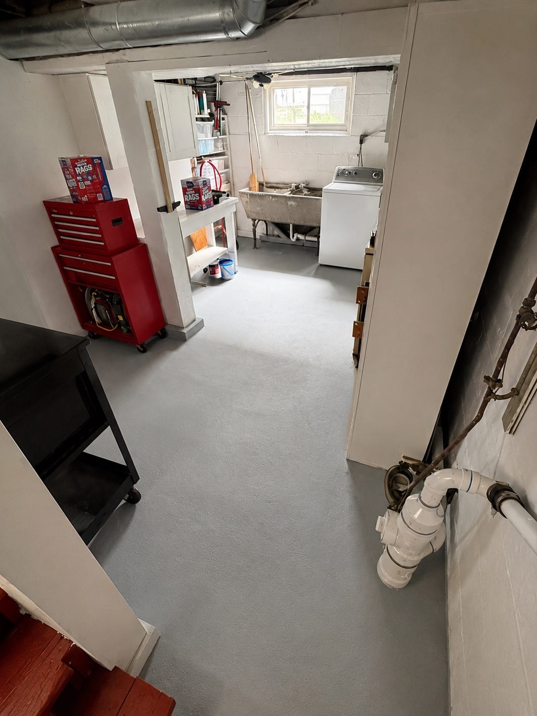 A basement floor finished with an even light-gray coating, cleared wall to wall