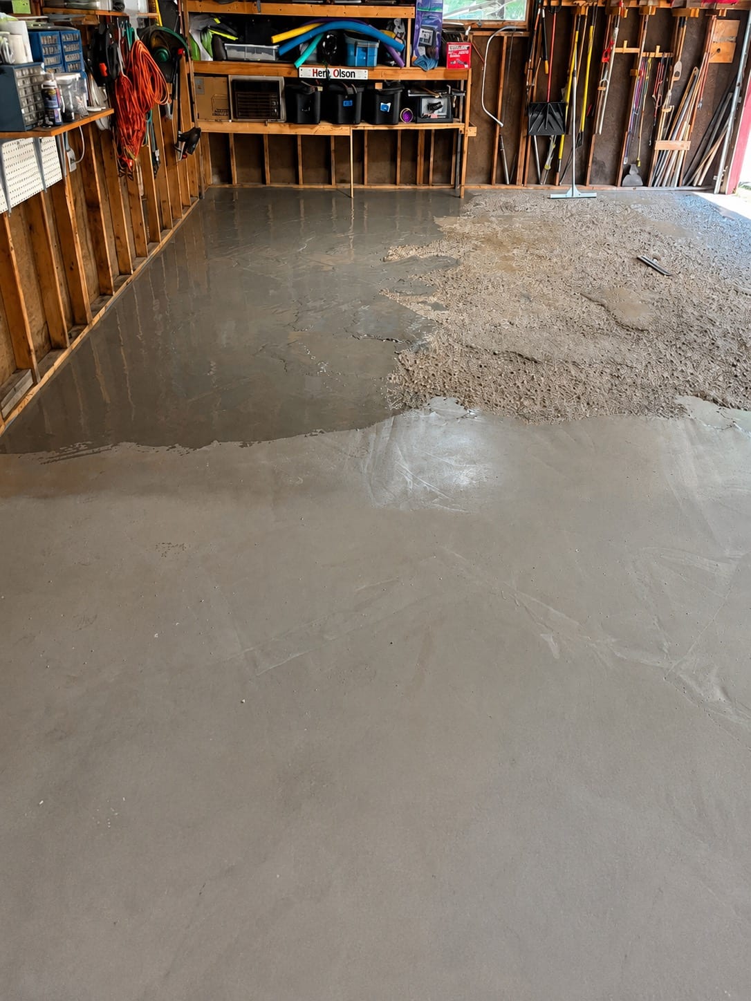 Garage slab during surface preparation, with a cleaned and wetted section meeting an unprepared dusty section along a visible line